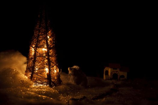 Polar bear next to a fake tree and house at background. Low light.