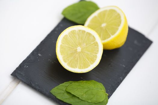 Lemon in halves on a blackboard with green leaves.