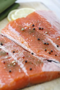 Two raw salmon pieces ready on a chopping board. Focus is on right fillet.