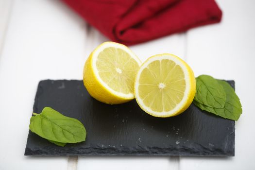 Lemon in halves on a blackboard with green leaves and red napkin.
