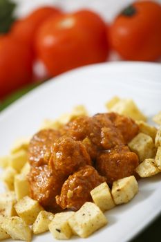 Meatballs with tomato sauce and fries around them.