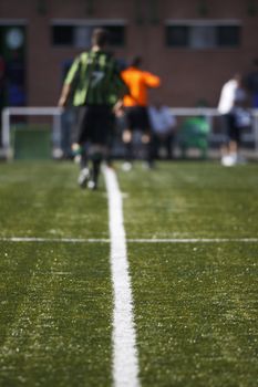 Detail of lines of soccer field with soccer players at background and out of focus.