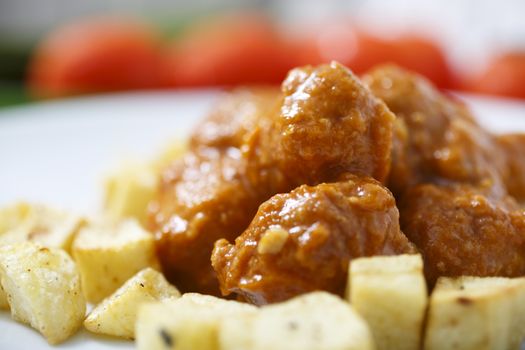 Meatballs with tomato sauce and fries around them.