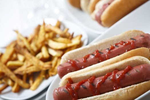 Hot dogs with fries and ketchup and more hot dogs at background.