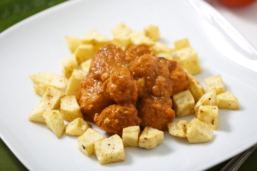 Meatballs with tomato sauce and fries around them.