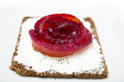 Appetizer of marinated salmon over a black bread with dill dyed with beetroot.