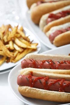 Hot dogs with fries and ketchup and more hot dogs at background.