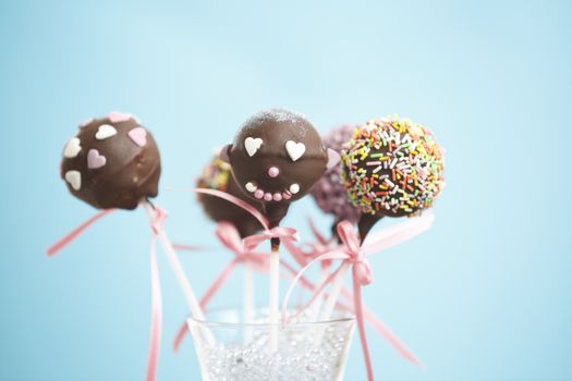 Cakepops over blue background with pink ribbon.