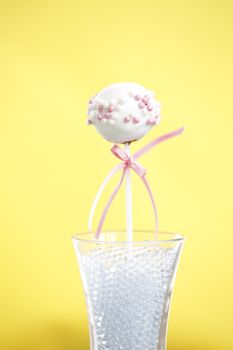 A single cakepop over yellow background.