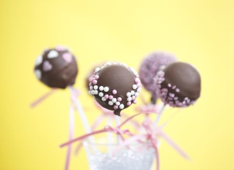 Cakepops over yellow background with pink ribbon.