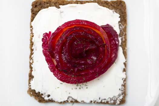 Appetizer of marinated salmon over a black bread with dill dyed with beetroot.