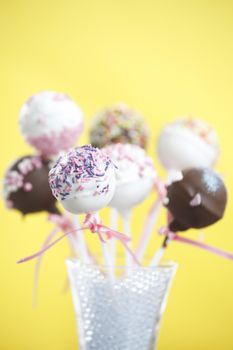 Cakepops over yellow background with pink ribbon.