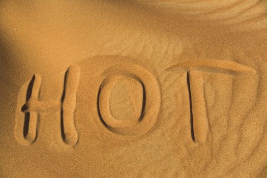 The word hot writen on the sand in desert