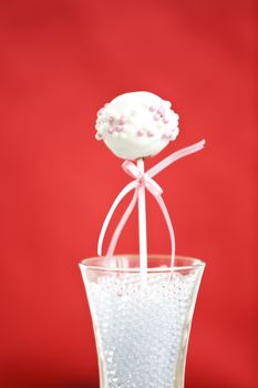 A single cakepop over red background.