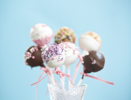 Cakepops over blue background with pink ribbon.