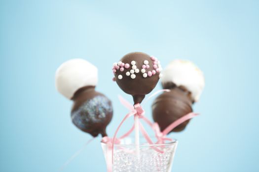 Cakepops over blue background with pink ribbon.