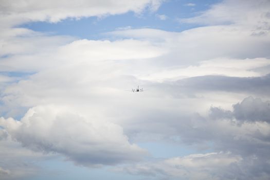 A private jet flying away among a cloudy sky