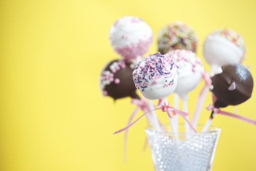 Cakepop over yellow background and space at the left.