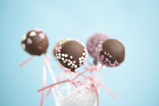 Cakepops over blue background with pink ribbon.