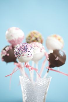 Cakepops over blue background with pink ribbon.