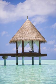 Bungalow over water in the lagoon. The bungalow is in the middle of the frame.