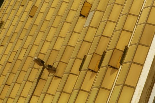 Image of the windows of a mirror building in Dubai. The color of the image is amber, some of the windows are opened. There is a street lamp at bottom.