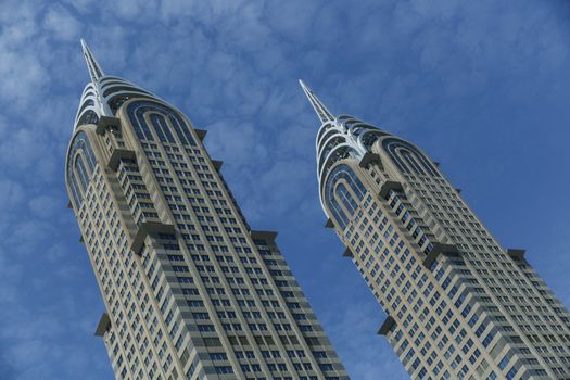 Beautiful buildings, from a personal perspective. The color of the image is blue, giving to the image a business look. The sky is beauty, clear, blue and it has a little bit clouds.