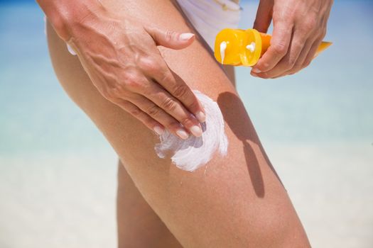 Woman applying sunscreen on leg to make aware about the importance of protection when going on holiday to sunny places.