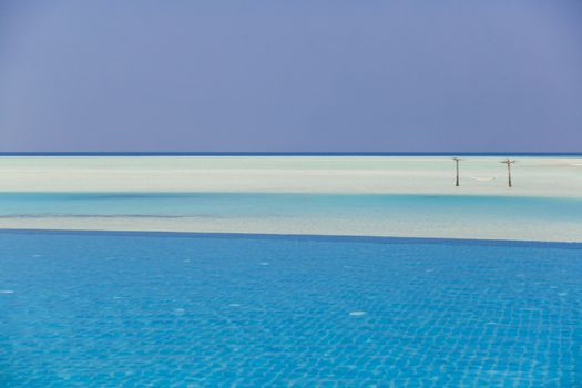 Swimming pool in front with hammock at background.