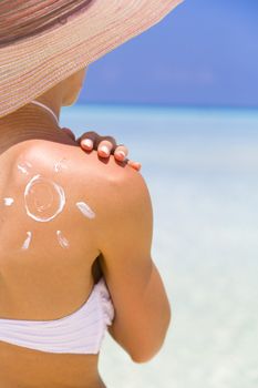 Sun painted with sunscreen on shoulder to make aware about the importance of protection when going on holiday to sunny places.