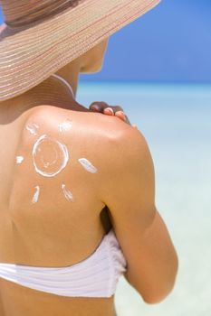 Sun painted with sunscreen on shoulder to make aware about the importance of protection when going on holiday to sunny places.