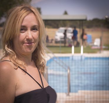 Portrait of blond woman with swimsuit and pool background