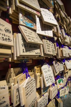 Tokyo, Japan - March 26, 2016: A wall of wooden wishing plaques. One front of ema has space for writing one wish and another front usually have decorated illustration s