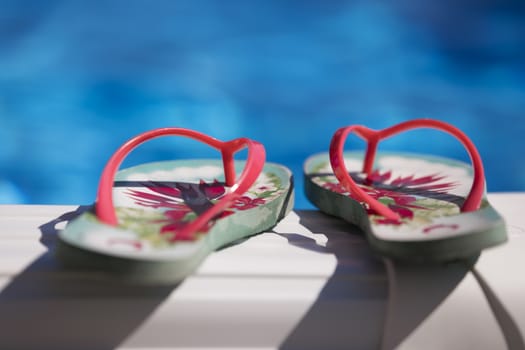 Flip flops on the edge of the swimming pool