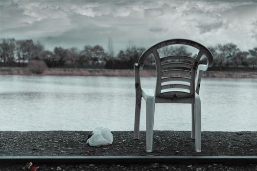 Abandoned chair in an old rail way in the river, atmosphere added.