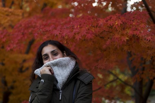 Girl covering his face with her scarf in the fall