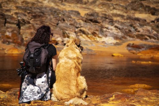 Woman sitting in the edge of Rio Tinto with her dog