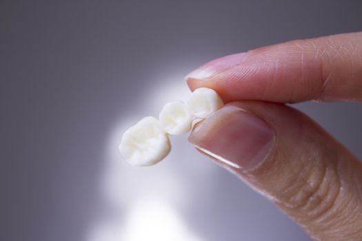 False teeth gripped by the hand of a woman
