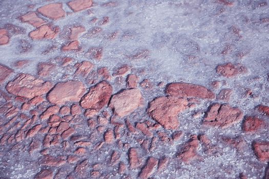 Textured of different shapes of rocks of salt in a pink water basin.