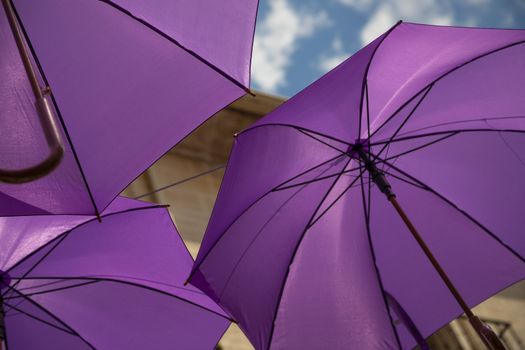 Background of purple umbrellas seen from bottom view in a small city. The very inhabitants were the one creating this art in the street during the Lavender season in a Festival in July. The Festival was held in July the 7th 2019 in a small city called Brihuega, in Guadalajara. SPAIN.