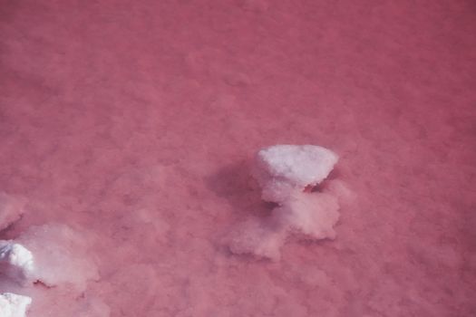 Textured of different shapes of rocks of salt in a pink water basin.