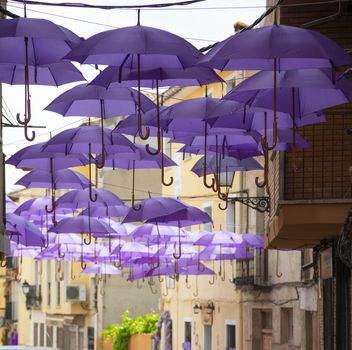 Background of purple umbrellas seen from bottom view in a small city. The very inhabitants were the one creating this art in the street during the Lavender season in a Festival in July. The Festival was held in July the 7th 2019 in a small city called Brihuega, in Guadalajara. SPAIN.