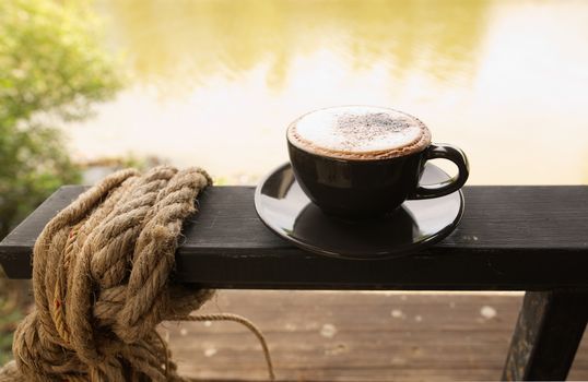 Hot mocha coffee or Cappuccino in the brown cup on the wooden table.