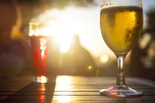 Red wine and cold beer against the sun with male silhouette at background