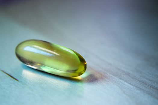 Yellow capsule of fish oil on wooden table