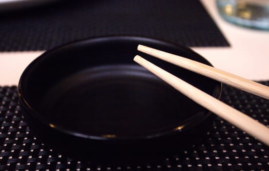 Chinese chopsticks on empty black bowl