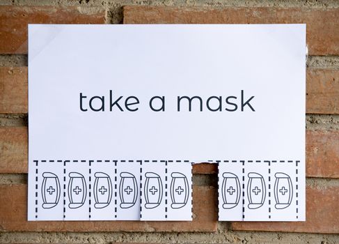 Tear off paper on brick wall with phrase "take a mask". Be responsible on what you do.