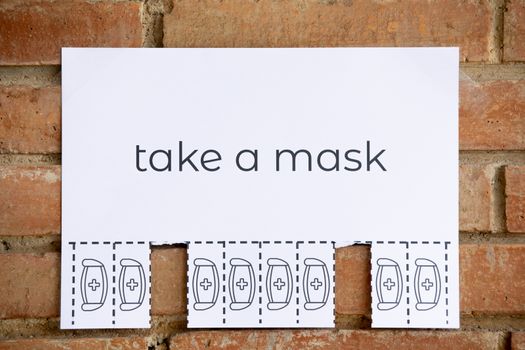 Tear off paper on brick wall with phrase "take a mask". Be responsible on what you do.