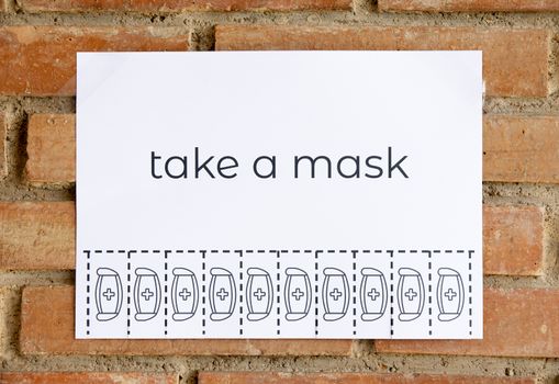 Tear off paper on brick wall with phrase "take a mask". Be responsible on what you do.