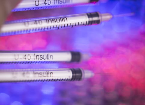 Insulin syringes on multicolored background out of focus